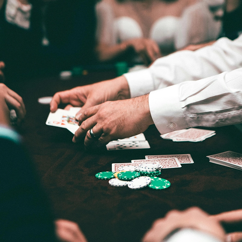 A person dealing cards in a poker game with chips on the table.